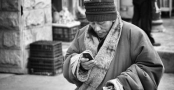 old man in a faraway country looking at a mobile phone