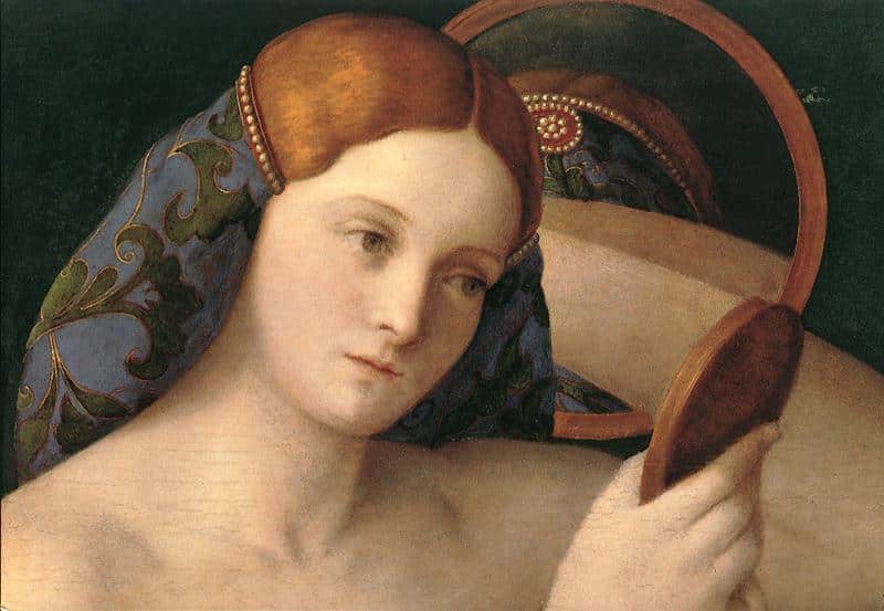 woman look into a mirror she is holding 